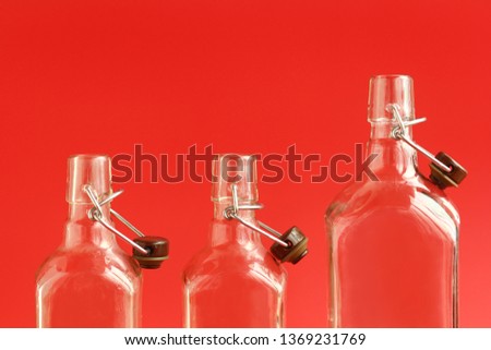 Closeup of three glass empty open bottles over red background