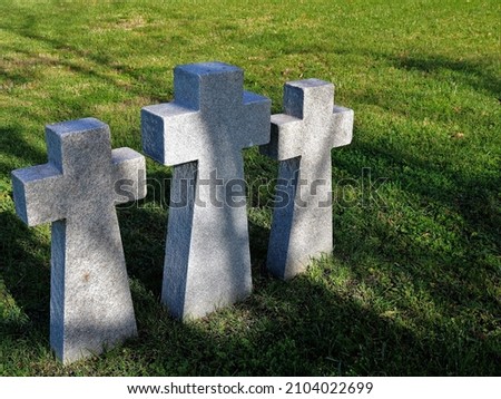 close-up of three granite tombstone crucifixes on a green lawn as a symbol of loss, sorrow and sadness, stone crosses on the mass graves of soldiers, Catholic symbols in the landscape of the cemetery