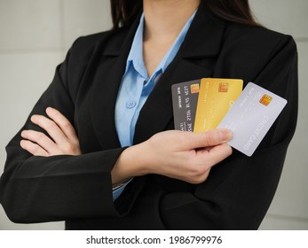 Close-up Of Three Mockup Credit Cards In A Businesswoman's Hands, A Businesswoman In A Black Suit With Arms Closed Is Holding Three Mockup Credit Cards In Her Right Hand.