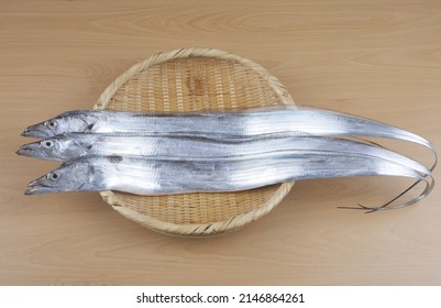 Close-up Of Three Raw Silver Cutlassfish With Straight Body On A Bamboo Basket, South Korea
