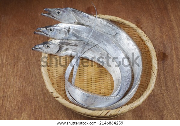 Close-up of three raw silver cutlassfish\
with round body on a bamboo basket, South\
Korea\
