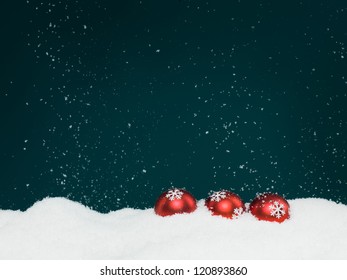 closeup of three red colored christmas globes decorated with glittery snowflakes surrounded with snow, on blue background with falling snowflakes - Powered by Shutterstock