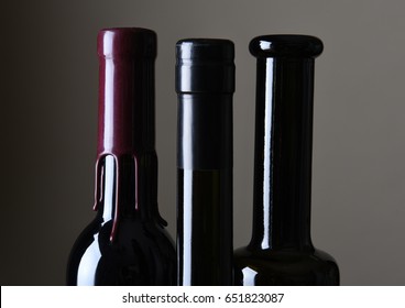 Closeup of three wine bottle necks against a light ot dark gray background. - Powered by Shutterstock