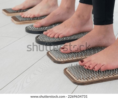 Close-up of three women's feet on sadhu's nails. 
