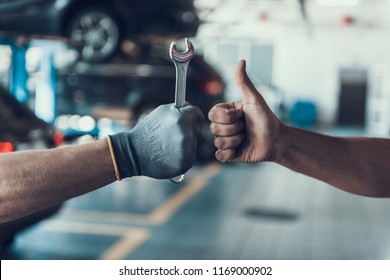 Close-up Thumb Up and Mechanics Hand with Tool. Automobile Master Wearing Gloves Showing Positive Gesture after Finishing Work. Technic occupation. Automobile Repair Service Concept.
