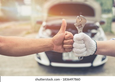 Close-up Thumb Up and mechanics working in auto service. One is holding a spanner while the other is showing Ok sign, Technic occupation. Automobile Repair Service Concept. - Powered by Shutterstock