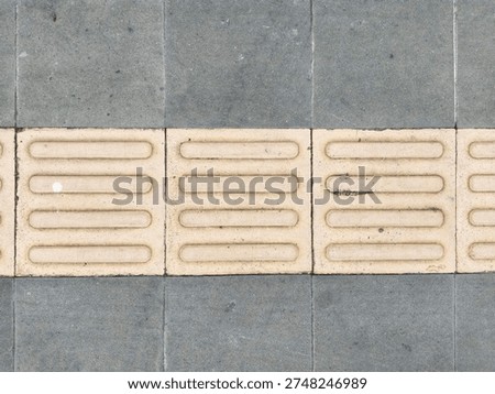 Close-up of a tiled pavement surface with a rough, porous surface equipped with a guide tile facility, Tactile Tiles, in yellow