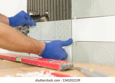 Closeup Of Tiler Hand Laying Ceramic Tile On Wall In Kitchen, Renovation, Repair, Construction.