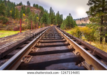 A close-up, tilt shift view of a train trestle and tracks on an overcast day