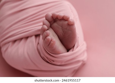 Close-up of tiny, cute, bare toes, heels and feet of a newborn girl, boy. Baby foot on pink soft coverlet, blanket. Detail of a newborn baby legs. Macro horizontal professional studio photo. 