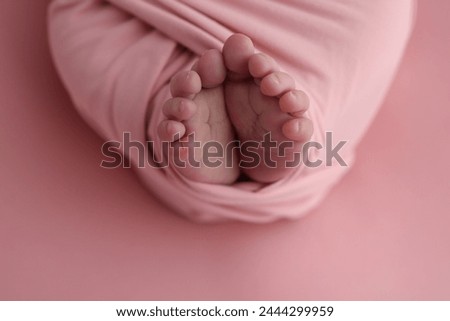 Close-up of tiny, cute, bare toes, heels and feet of a newborn girl, boy. Baby foot on pink soft coverlet, blanket. Detail of a newborn baby legs. Macro horizontal professional studio photo. 