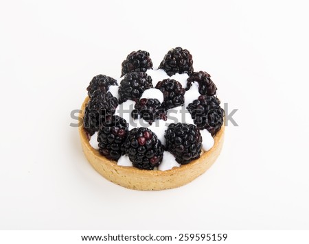 close-up of a tiny tart with black raspberry on top isolated on white background
