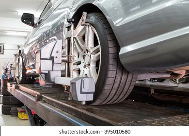 Closeup Of Tire Clamped With Aligner Undergoing Auto Wheel Alignment In Garage