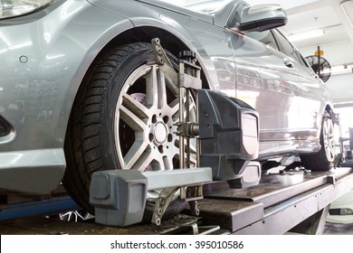 Closeup Of Tire Clamped With Aligner Undergoing Auto Wheel Alignment In Garage