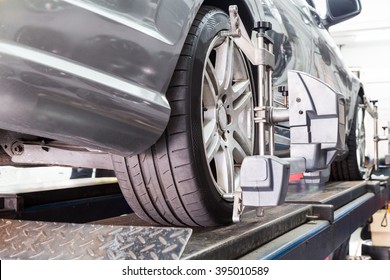 Closeup Of Tire Clamped With Aligner Undergoing Auto Wheel Alignment In Garage