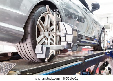 Closeup Of Tire Clamped With Aligner Undergoing Auto Wheel Alignment In Garage