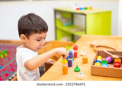 Closeup of toddler boy playing with wooden peg dolls with cups and hats sorter toys
