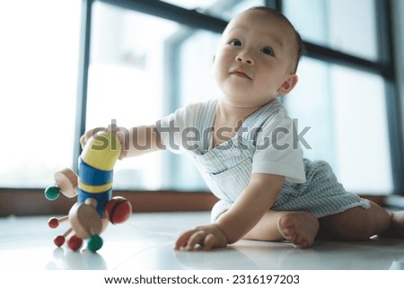 Closeup of a toddler crawling on knees at home moving towards a small toy during a bright new fresh day with large windows in background