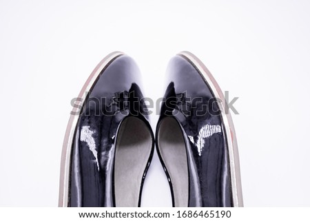 Close-up of the toes of black patent leather shoes on a white background
