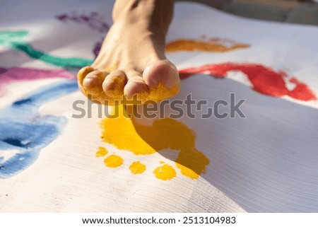 Close-up of the toes of children's bare feet, painted yellow for imprinting on paper. creative concept, children playing with paints, freedom of creativity. Interesting fun childhood