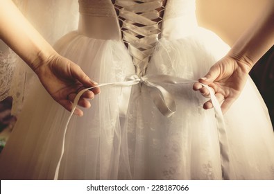 Closeup toned photo of beautiful bride tying up her wedding dress - Shutterstock ID 228187066