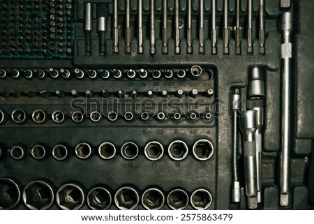 Close-up of a toolset including various screwdrivers, sockets, and extensions in a compact organizer. Metallic tools neatly arranged, suitable for repair work.