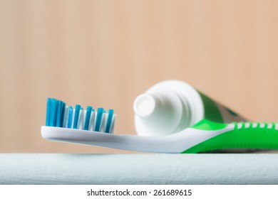 Close-up Of A Toothbrush And Tube Of Toothpaste On The Edge Of A Bathroom Counter From A Low Angle View.