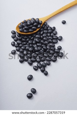 Close-up and top angle view of dried Seoritae(black beans) on a wood spoon and white floor, South Korea
