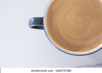 A Closeup Top Down View Of A Mug Of Hot Mocha Coffee On A White Counter In A Cafe Setting.