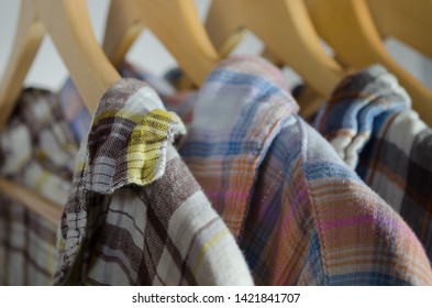 Closeup Of Top Of Flannel Shirts Hung On Wood Hangers