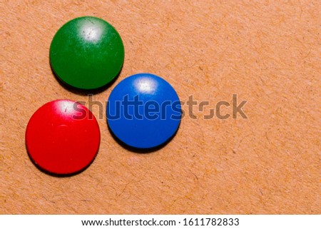 Closeup of top of three thumb tacks stuck into cardboard