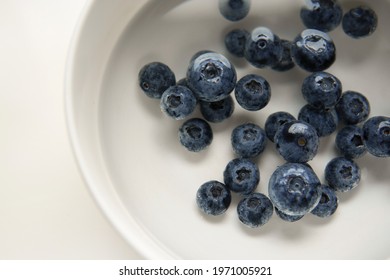 Closeup Top View Above Soaking Pile Group Fresh Organic Picked Blueberries With Cold Water Mixed Vinegar In A White Bowl Background. Washing For Reduce And Remove Bacterial Before Eating Concept