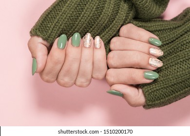 Closeup top view of beautiful two faded colors trendy manicure of  green and pink nails with glossy silver stamp design isolated on pastel pink background. Winter or autumn style of nail design concep