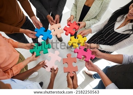 Closeup top view of diverse businesspeople connect jigsaw puzzle pieces motivated for shared business goal or success. Employees engaged in teambuilding activity at company training or meeting.