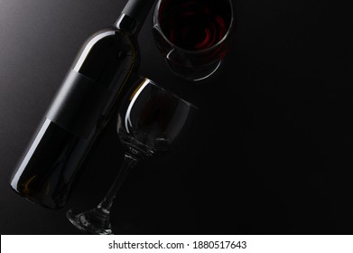 Close-up top view of elegant dark bottle and glasses with remains of red wine on rustic black background. Advertising and promotion concept. Mock up. Flat lay. View from above. Space for text. - Powered by Shutterstock