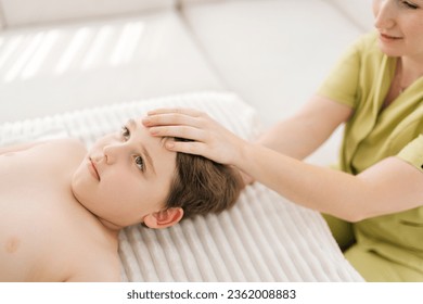 Closeup top view of five year old boy receiving osteopathic or chiropractic treatment in pediatric clinic. Close up of female osteopath doing physiological skull therapy. Concept of healthy childcare. - Powered by Shutterstock