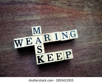 Close-up Top View Image Of Square Wood Blocks Crossword With The Words KEEP WEARING MASK Isolated On The Wooden Ground.