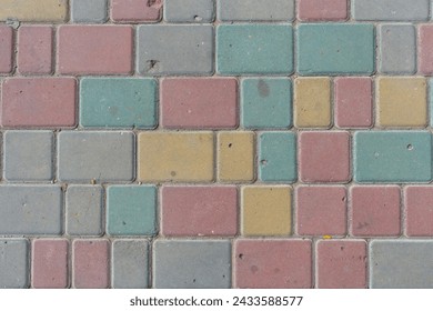 Close-up top view of multi colored tiled stine sidewalk on pedestrian city street. Copy space for your text or decoration. Abstract road background theme.