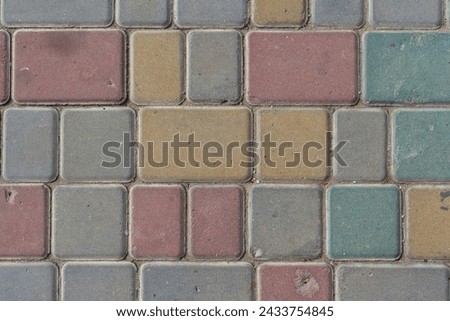 Close-up top view of multi colored tiled stine sidewalk on pedestrian city street. Copy space for your text or decoration. Abstract road background theme.