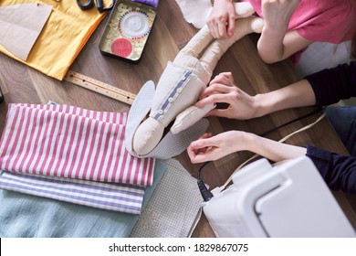 Close-up top view on the creative process of sewing rag bunny doll, details of doll cloth children hands sewing machine on the table background