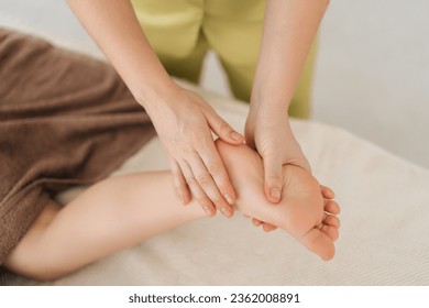 Close-up top view of unrecognizable female masseur doing therapeutic massaging heel foot of five year old boy client lying on massage table in spa salon. Concept of healthy childcare. - Powered by Shutterstock