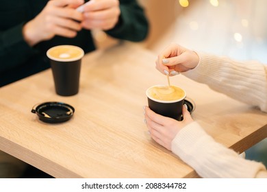 Close-up top view of woman and man sitting in cafe holding warm cups of coffee on table having fun conversation. Young couple enjoying time spending with each other sitting at table in coffee shop - Shutterstock ID 2088344782
