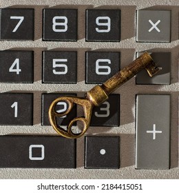 Close-up Top-down View Of Antique Brass Key Resting On Calculator Keyboard. Key Is Side Lit With Shadows And Highlights