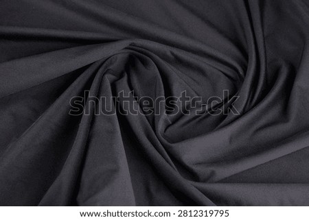 Close-up top-down view of shiny black dry-fit fabric with a twisted, folded polyamide texture.