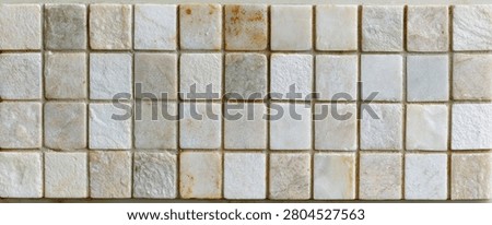 A close-up, top-down view of a textured surface composed of numerous small, square mosaic tiles made from natural stone.