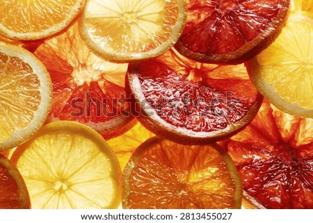 A close-up, top-down view of thinly sliced oranges and blood oranges, showcasing their juicy textures and vibrant colors.