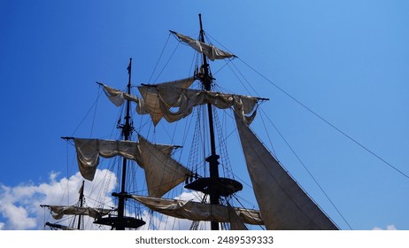 Close-up of the tops of sailing boat masts and old rigging, half rowed or folded, in preparation for a tourist and cultural cruise, pleasure and technical work, full of ropes and storage, moored - Powered by Shutterstock