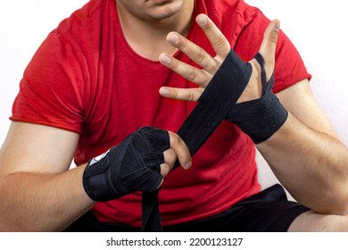 Closeup torso of caucasian man wearing sportswear and bandaging his hands with boxing bandages. Moment before sport match or training, preparing fighting concept. Copy space, white background. - Powered by Shutterstock