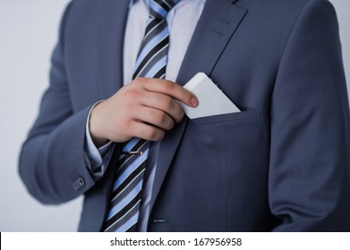 Closeup of torso of confident business man wearing elegant suit taking mobile phone from pocket