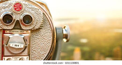 Closeup of tourist coin operated binoculars at New York City with Central Park blurred on background